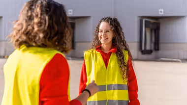 Two women dressed in high-visibility clothing having a conversation