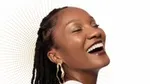 An image to promote Dove Regenerative dermocosmetics skincare products. A Black woman is shown in side profile, smiling. Background is white with gold dots.